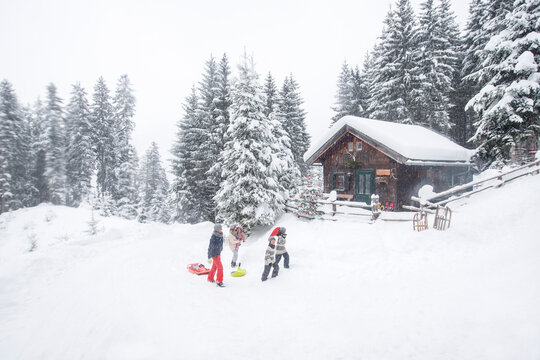 Austria, Altenmarkt-Zauchensee, family with sledges at wooden house at Christmas time