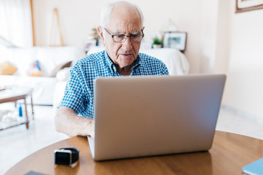 Porrtait of senior man at home learning to use laptop