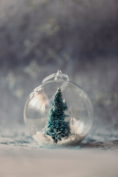 Christmas bauble made of glass with fir tree and artificial snow inside