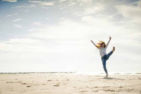 Happy woman having fun at the beach, dancing in the sand