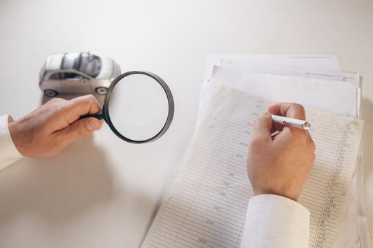 A man examines the car cataract with a magnifying glass.