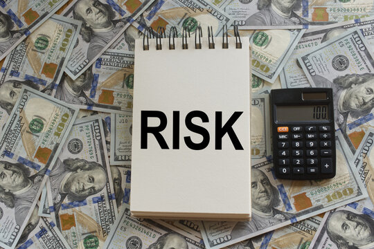 Notebook with the Word &ldquo;Risk&rdquo; on Hundred-Dollar Bills and a Calculator, Concept of Investment Risk and Financial Decision-Making.