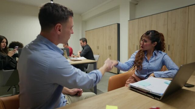 Businesspeople shake hands to finalize a deal in a modern office. Coworkers conclude a successful agreement with a firm handshake.