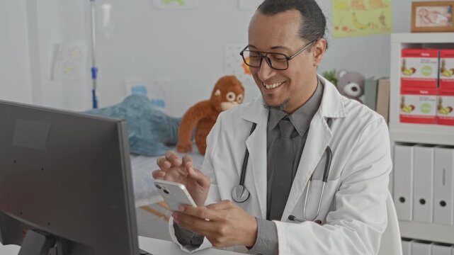 Man doctor in clinic taps smartphone with index finger while stethoscope rests on his neck and computer monitor shows records; friendly care telemedicine.