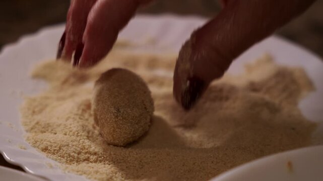 Coating Spanish Croquette with Breadcrumb. Woman Hand Rolling Homemade Croquetas in Breadcrumbs Closeup shot.
