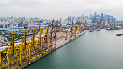 Obraz premium Aerial View of Industrial Shipping Port with Yellow Cranes and City Skyline
