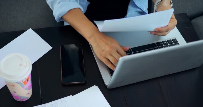 Focused work environment. Worker diligently sorting files on organized desk with device nearby. Person concentrating on document editing while managing multiple devices in clean workspace