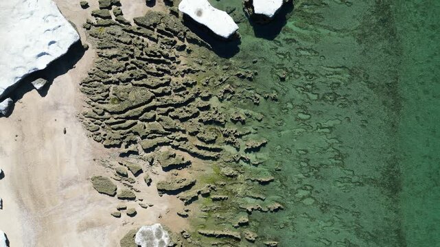 Aerial top down view of rocky coastline and turquoise Atlantic Ocean near Puerto Piramides on Valdes Peninsula Argentina