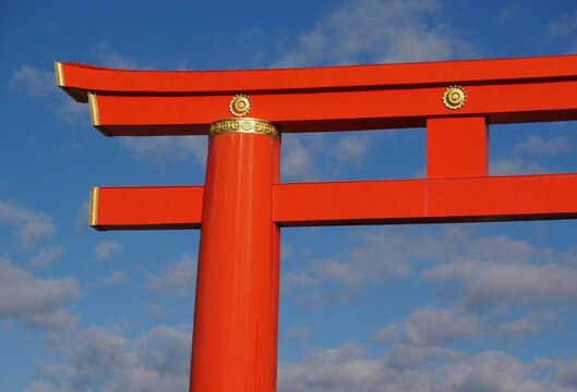The iconic giant vermilion Torii gate of Heian Jingu Shrine standing grandly under a clear blue sky in Kyoto, Japan.