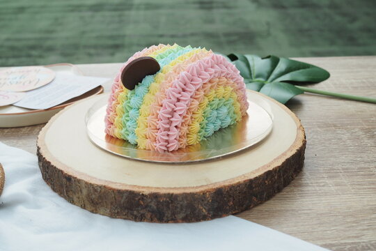 A beautiful rainbow shape cake with rainbow color, cute birthday cake on wooden tray. Selective focus.