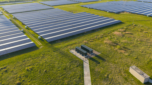 Aerial view of rows of solar panels in a large photovoltaic power plant surrounded by green fields Farmsum, Groningen, Netherlands.