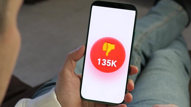 Close-up of viral negative feedback. A red dislike counter surges on a smartphone app. High-impact footage for social media marketing, reputation repair, customer dissatisfaction, and digital trends