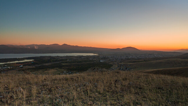 Sunset over the hills near Lake Sevan, Armenia, with orange light and quiet countryside atmosphere. Peaceful nature and mountain landscape.