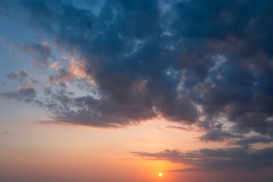 A beautiful sunset unfolds with a glowing orange sun on the horizon