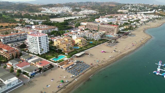 High angle view of Benalmadena coastline near Malaga, Spain. Scenic resort beach with blue sea waves, golden sand, beachfront luxury hotels, and holiday villas on the Costa del Sol.