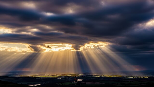 Golden sun rays shining through stormy clouds onto a landscape.