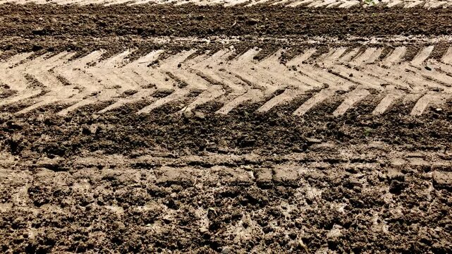 Agricultural field in the rural countryside, tilled and prepared for planting crops, muddy ground or soil with furrows and tractor tire tracks in Germany, Europe