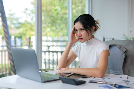 Young businesswoman suffering from headache and stress, overworking in a modern office or home, feeling overwhelmed and exhausted