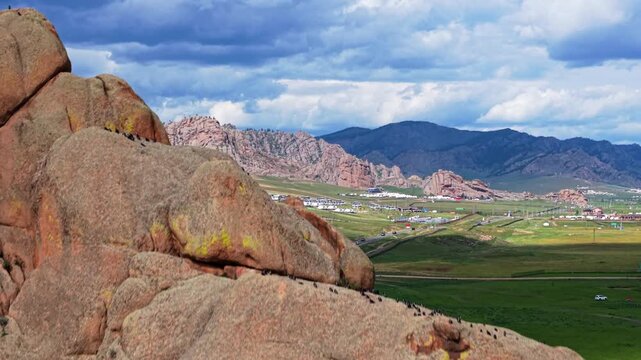 Mongolian Steppe Revealing Traditional Yurts, Wandering Cattle, Vehicles Traversing Rocky Terrain And Verdant Pastures Beneath Overcast Skies. Rock Formation In Terelj National Park, Mongolia