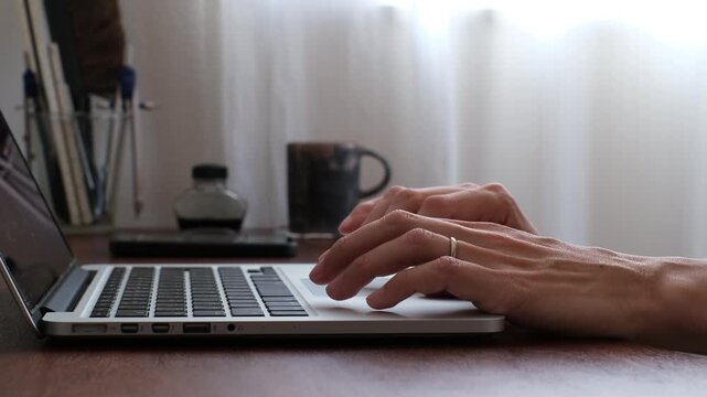 Close-up of hand using laptop trackpad at home office desk
在宅ワーク環境でノートパソコンのトラックパッドを操作する手元のクローズアップ