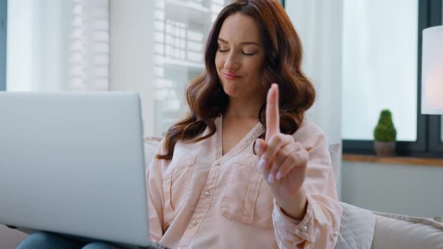 Caucasian woman using laptop looking at camera shaking finger negative no not gesture reject sign relaxing on couch at home female girl with computer device showing denied disagree resting on sofa