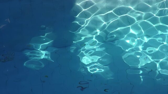 Swimming pool illuminated by sunlight. Light reflecting on the water creating a pattern