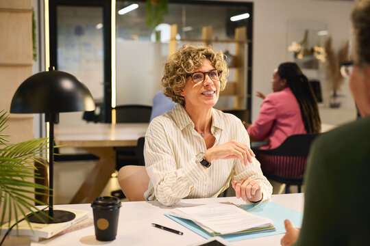 Mature businesswoman working with colleagues at desk in creative office