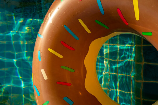 Colorful inflatable donut floating in sunny resort pool, vibrant summer water texture. Concept: pool vacation