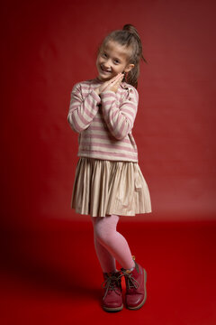 Smiling Little Girl Posing in Studio. Full Length Child Portrait with Playful Expression and Fashionable Clothing