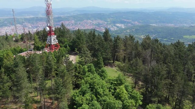 Drone flying backwards from telecommunication tower on mountain top