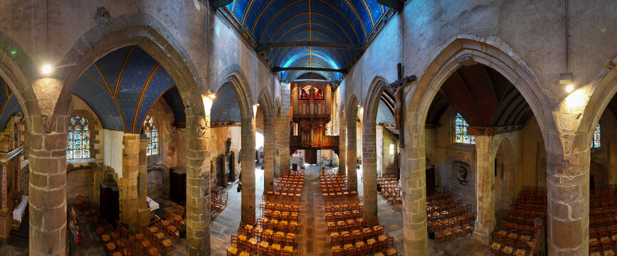 Aerial view of Eglise Saint-Melaine de Morlaix featuring a blue vaulted ceiling with gold stars, stone arches, and rows of wooden pews in Morlaix, Bretagne, France.