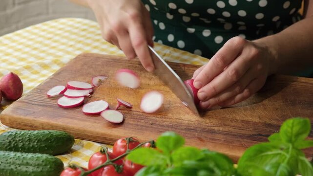 Cooking diet summer food. Woman slicing fresh garden radish to make vegetable salad. Preparing vegetarian healthy meal.
