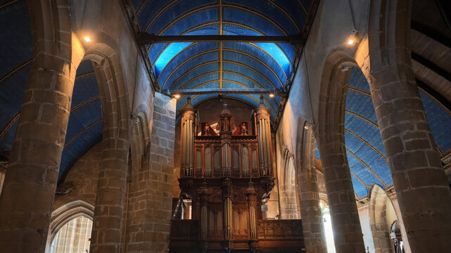 Aerial view of the interior of Eglise Saint-Melaine de Morlaix featuring a blue vaulted ceiling with stars and stone pillars in Morlaix, Bretagne, France.