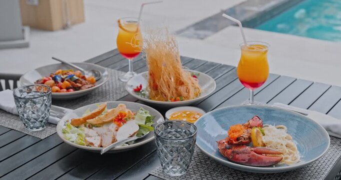 Lobster pasta and gourmet dishes served on outdoor table, poolside resort terrace, luxury vacation lifestyle and fine dining menu background