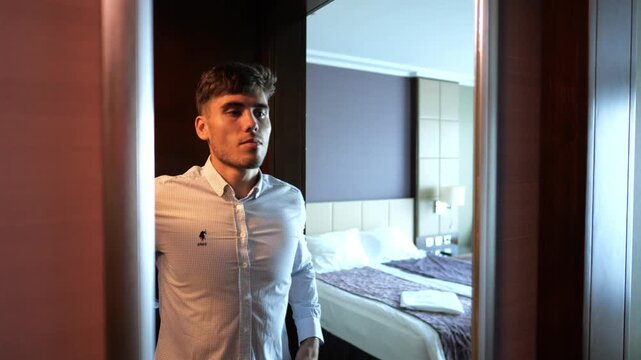 Young businessman adjusting shirt collar and cuffs in front of mirror in modern hotel room or apartment. Handsome manager prepare for business meeting or formal event showing professional lifestyle