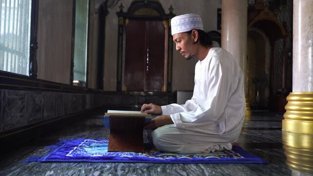 Muslim man reading the Holy Quran on a wooden stand, concept of Islamic wisdom, education and spiritual connection in mosque.