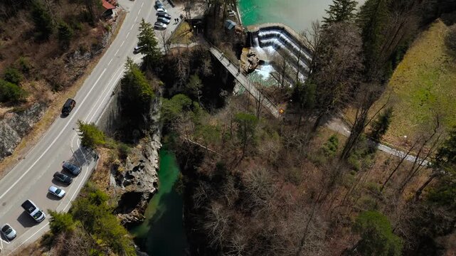 Drone video of Lechfall waterfall and the deep river gorge in Fuessen. Aerial perspective of mountain road infrastructure, alpine nature, and the tourist bridge at the Austria border.