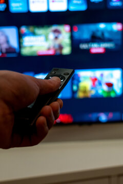 Person Holding Remote Control Toward Smart TV in Dark Room