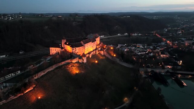 Burghausen Castle in Burghausen, Upper Bavaria, is longest castle complex in world aerial view, illuminated at night view from west. Palas of Burghausen Castle, Germany lake Woehrsee side sky shot. 