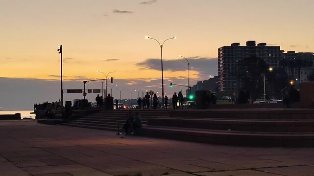 Big esplanade and people walking at rambla de montevideo city, at sunset winter day, barrio sur neighborhood, uruguay