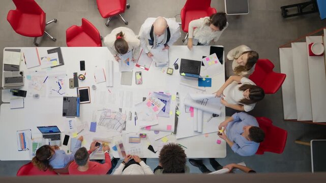 Coworkers collaborate energetically around a large table, reviewing documents and discussing project plans. Coworkers work together in a dynamic office, sharing ideas and brainstorming solutions.