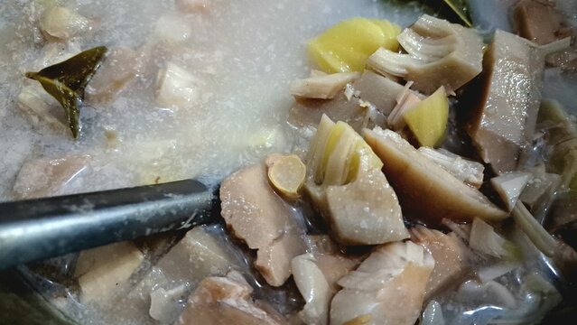 Stirring homemade tropical unripened jackfruit curry with metal ladle, high angle view of authentic Southeast Asian savory dish for restaurant menu backdrop