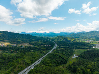 Obraz premium A high angle aerial view of a highway stretching through the green mountains and landscape of Wuyi Mountain in Fujian China