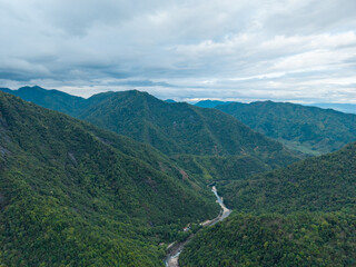 A scenic aerial view of green mountains and a river valley in Wuyi Mountain Fujian China under a cloudy sky © AS_SleepingPanda