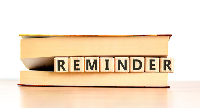 Reminder word symbol. Concept word Reminder on beautiful wooden blocks in beautiful book. Beautiful wooden table white background. Business support help reminder word concept. Copy space.