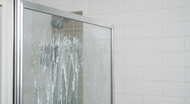 Soap scum on glass shower door. Bathroom cleaning and maintenance concept