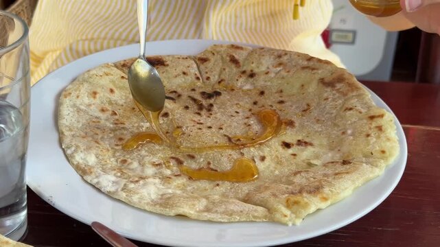 Sfakian pita with honey served on Crete, Greece. Traditional Cretan cheese pie on a white plate, close-up of honey being poured over warm handmade pastry.