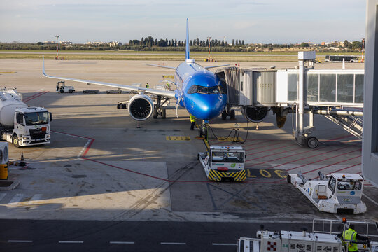 blue ita airways airbus a320neo parked at the terminal gate during ground handling operations at bari airport under a clear sky in golden hour light