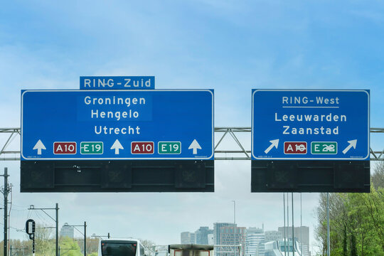 Daytime traffic on the A10 Amsterdam ring road with overhead signs for RING-Zuid and RING-West directing toward Groningen, Utrecht, Leeuwarden, and Zaanstad, Netherlands