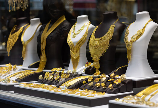 luxurious display of ornate 22k gold bridal necklaces and intricate filigree rings on mannequins in a high-end jewelry boutique window. elegant craftsmanship